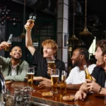 Group of friends celebrating a bachelor party in Las Vegas at 1923 Prohibition Bar, raising drinks together at the bar.