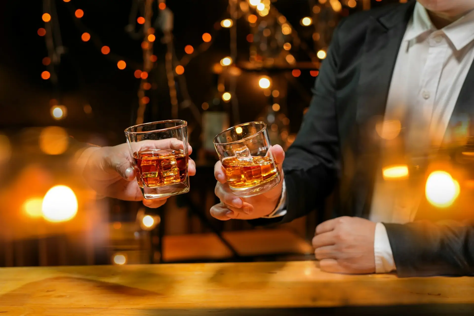 Two guests toasting with glasses of premium bourbon on the rocks inside 1923 Prohibition Bar, a hidden speakeasy bar located in Las Vegas.